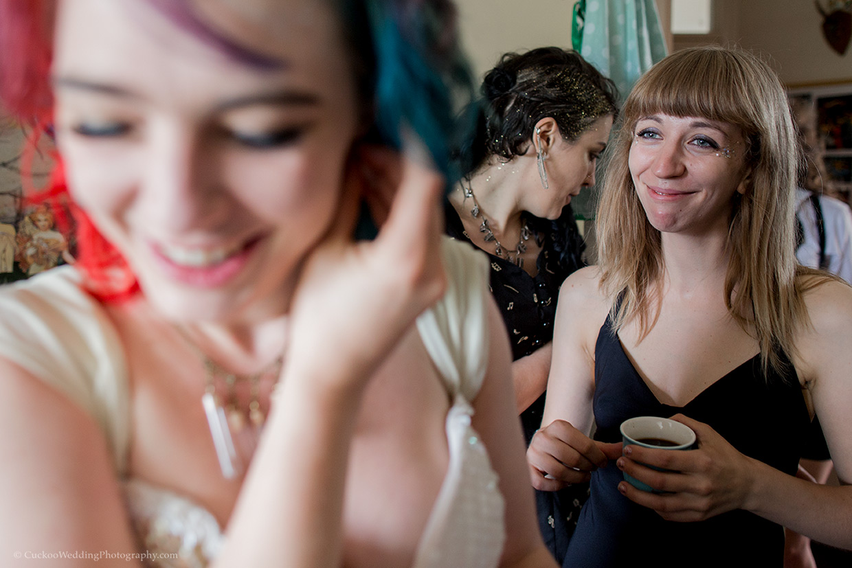 A bridesmaid looks at an alternative bride with a joyful expression. the bride is blurred and smiling.